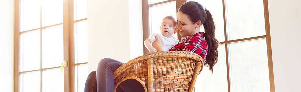 Mother sitting in a chair holding her little baby girl in her arms.