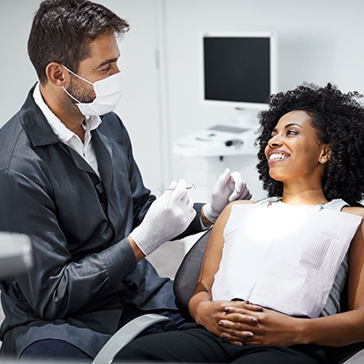 Dentist examining smiling female patient in clinic