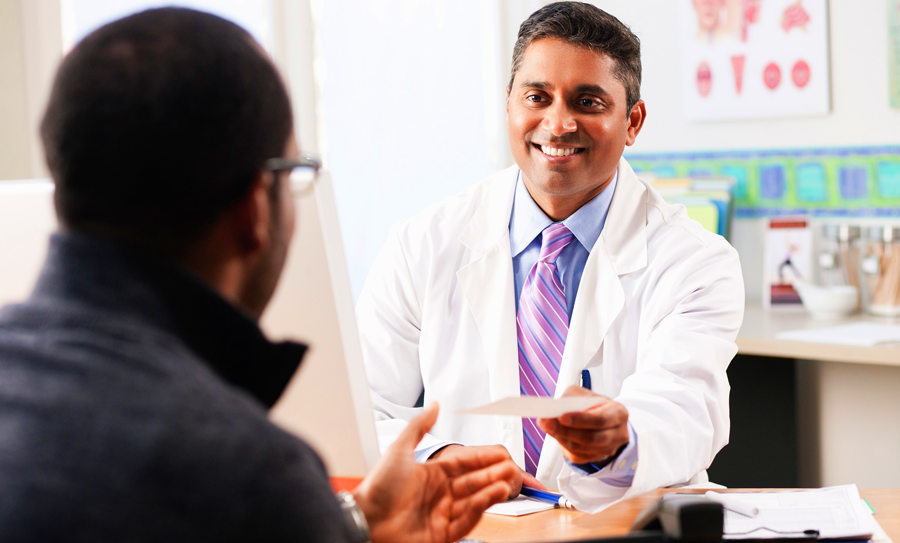 doctor sitting at a desk giving a patient a prescription