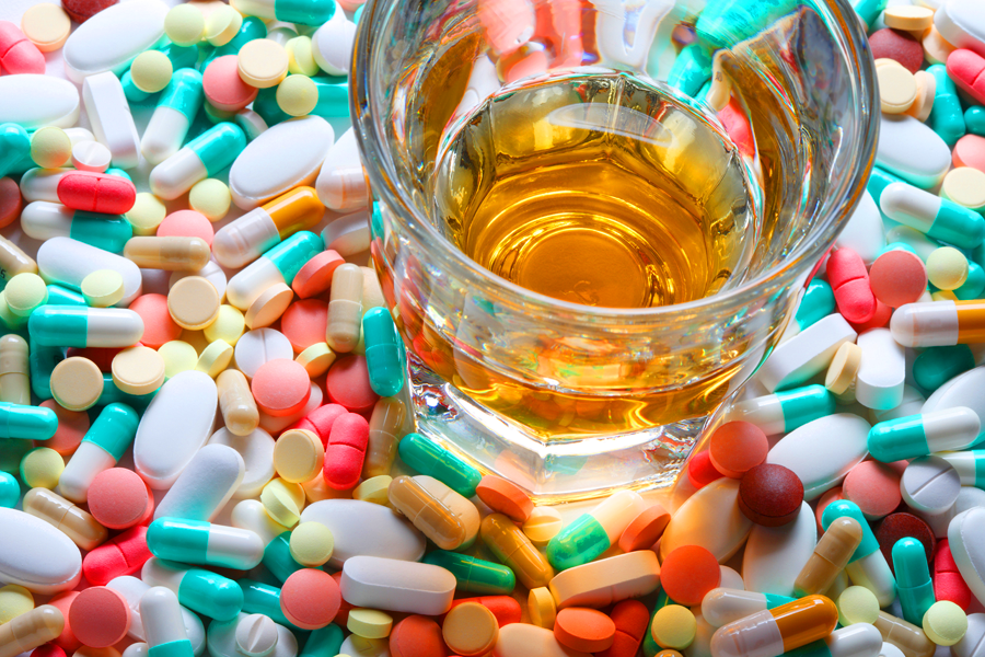 image of pills surrounding a glass of alcohol