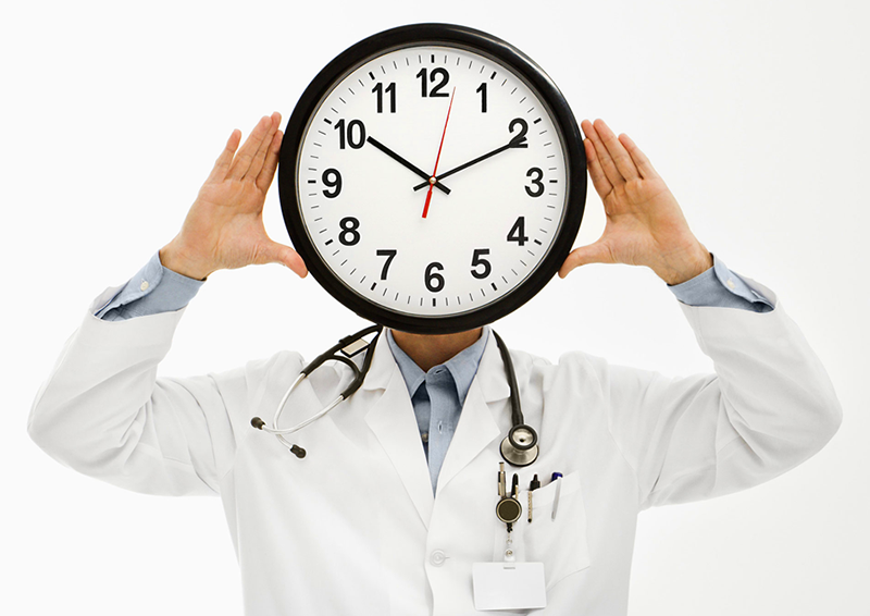 a doctor holding a clock in front of his face