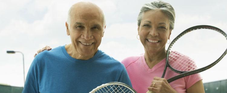 smiling older couple with tennis rackets