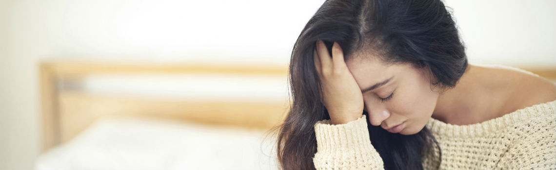 woman with closed eyes putting hands on her forehead