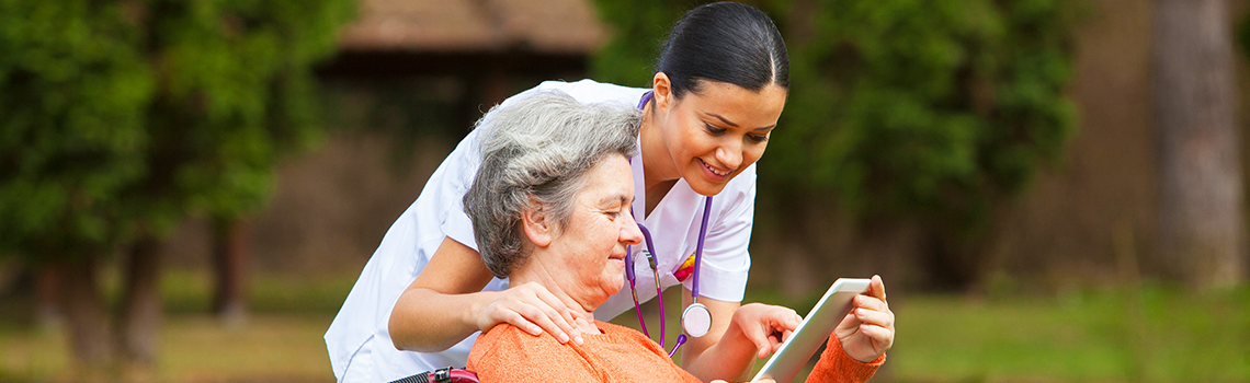 Nurse teaching woman in wheelchair how to use ipad