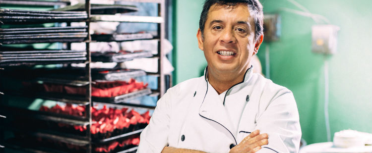 Baker in his kitchen with breads behind him