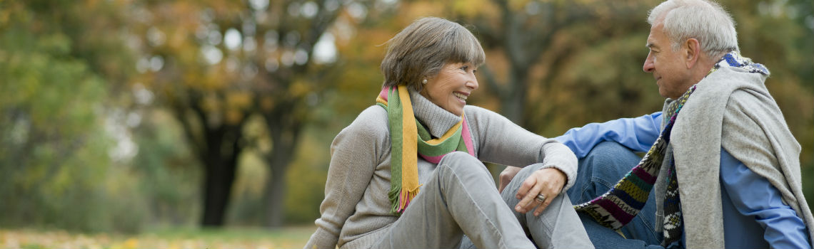 older couple speak while sitting in a park