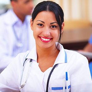 Medical doctor woman smiling indoors with her collegues working behind
