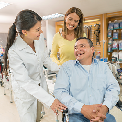 Man sitting in wheelchair and two women smiling Man sitting in wheelchair and two women smiling