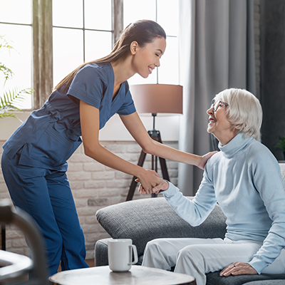 Happy female professional caregiver taking care of elderly woman at home