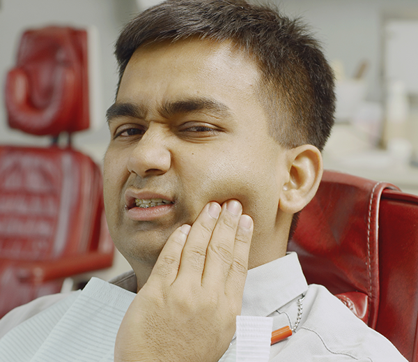 man holding cheek in pain