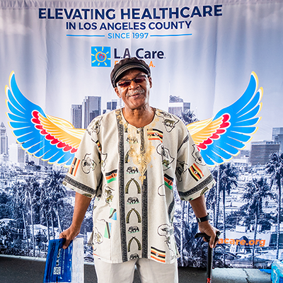 a man standing in front of L.A. Care's Elevating Health Care photo backdrop