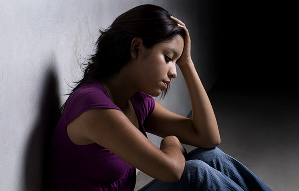 a young woman sitting against a wall