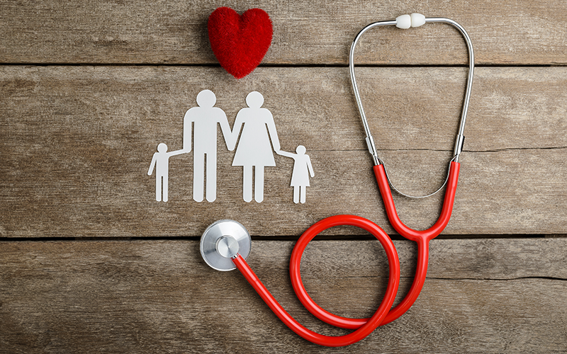 a paper family on a table with a stethoscope and a heart