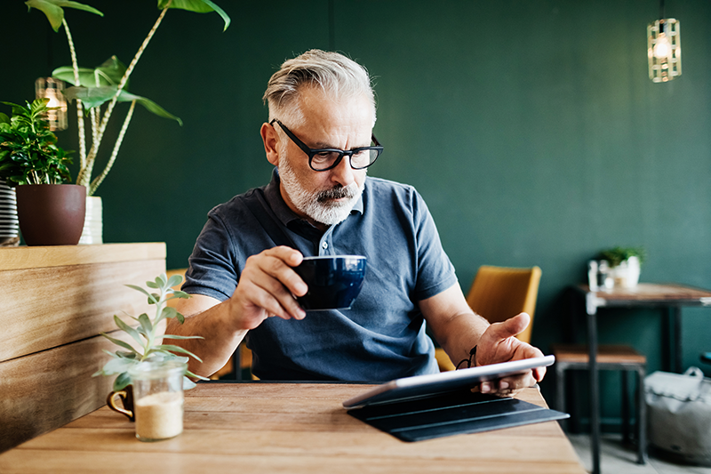 Person using tablet and drinking coffee
