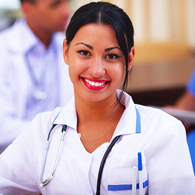 Medical doctor woman smiling indoors with her collegues working behind