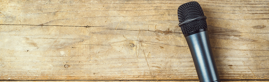 Microphone on a wooden office desk background. View from above.