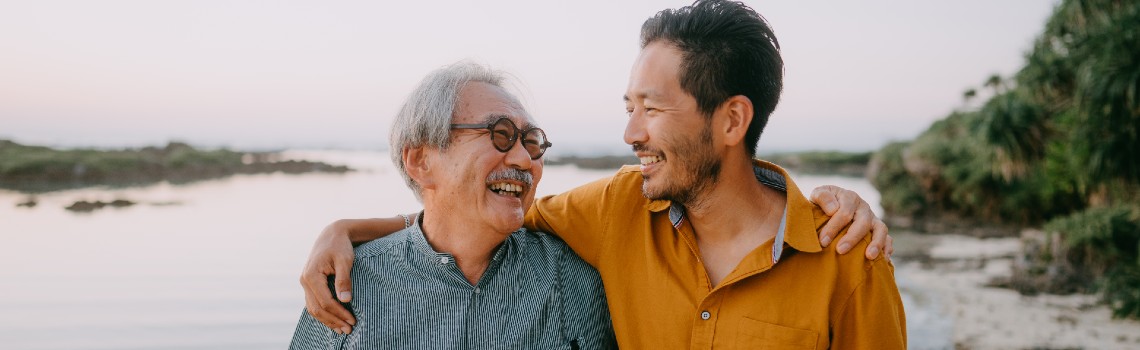 senior father and adult son share a walk on the beach