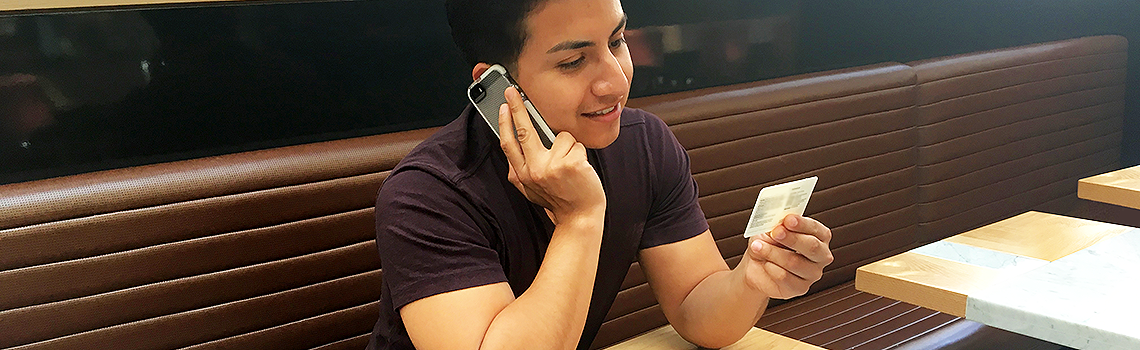 a young man calling customer service holding member ID card