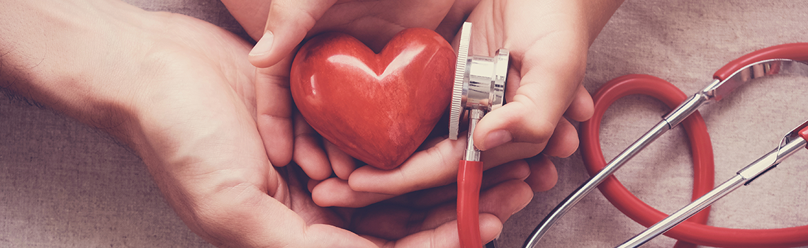 Child and adult holding red heart with stethoscope