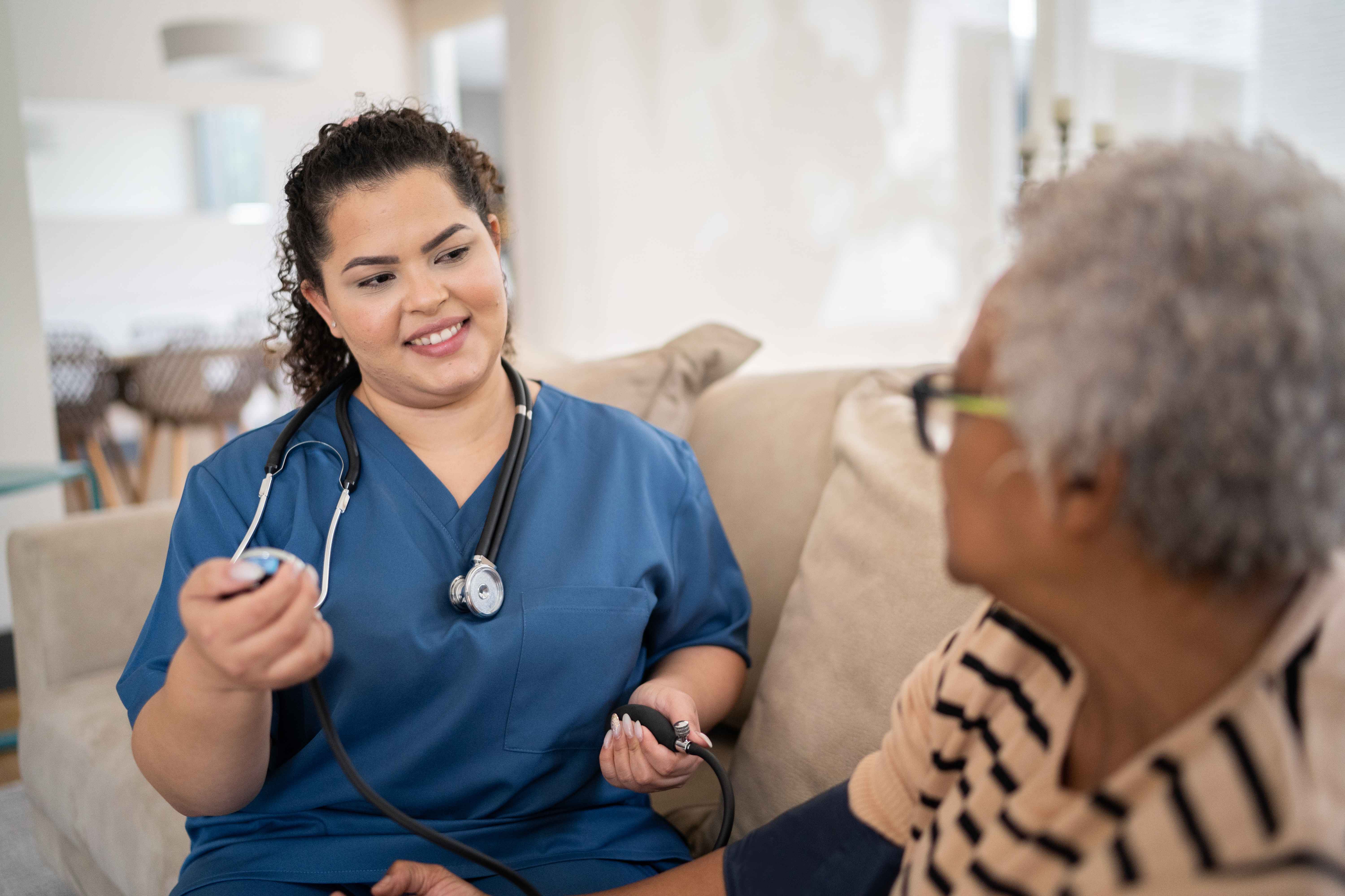 Healthcare worker taking blook pressure of patient at home