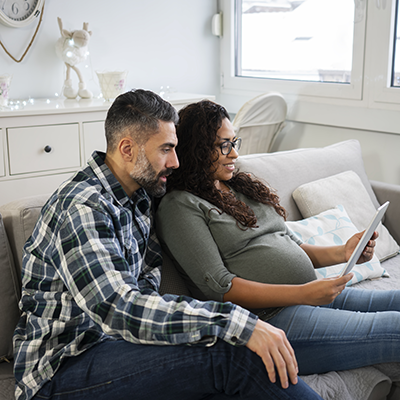man and pregnant woman looking at tablet